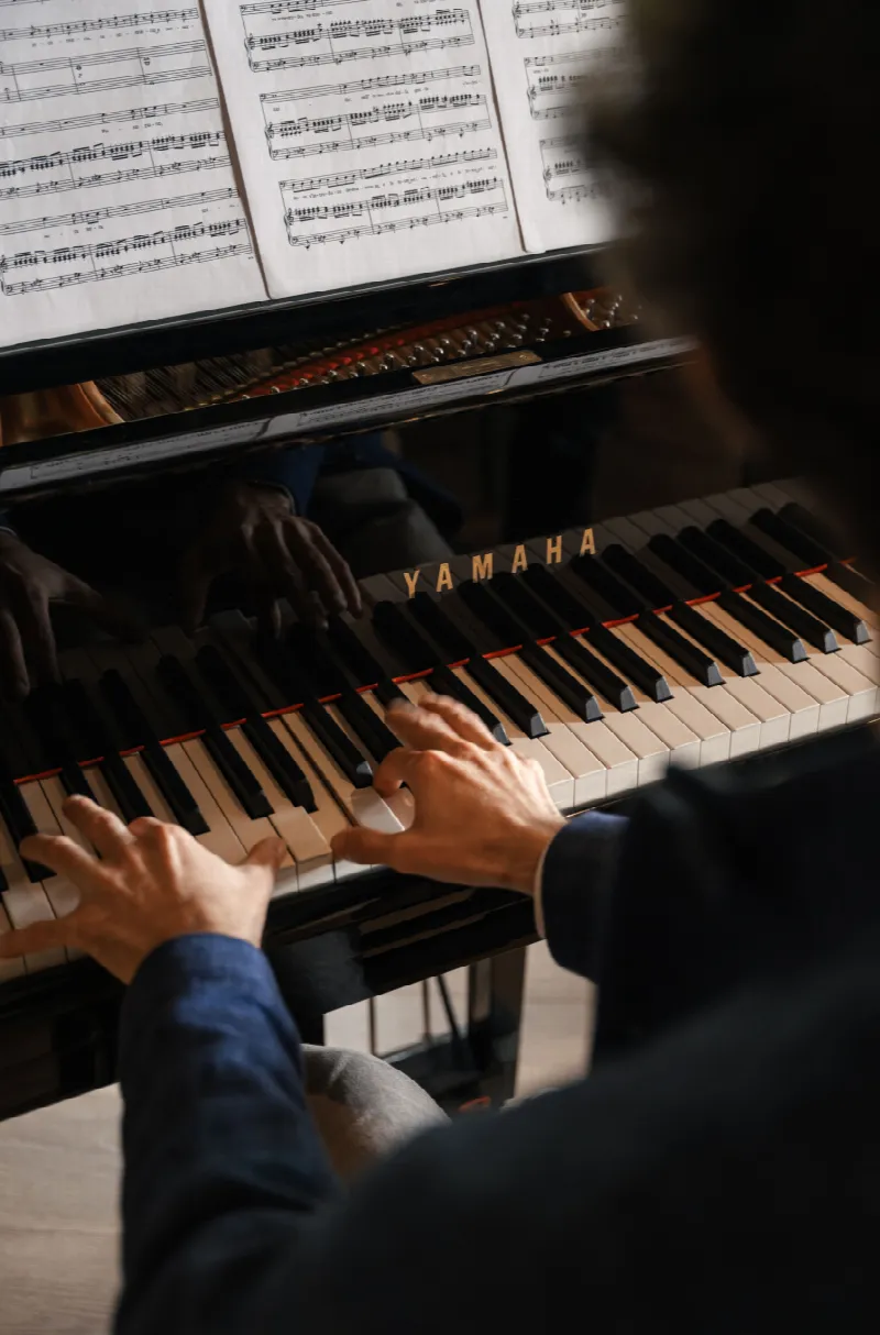 Detailaufnahme von Händen am Klavier mit Notenblättern auf einem Flügel im Kulturraum des Cyprianerhofs